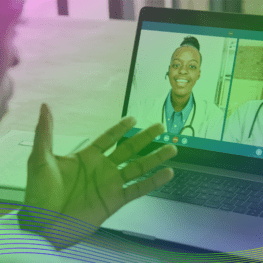 Healthcare professional in Doctor's scrubs 7is using a laptop to communicate with other healthcare professionals via video.